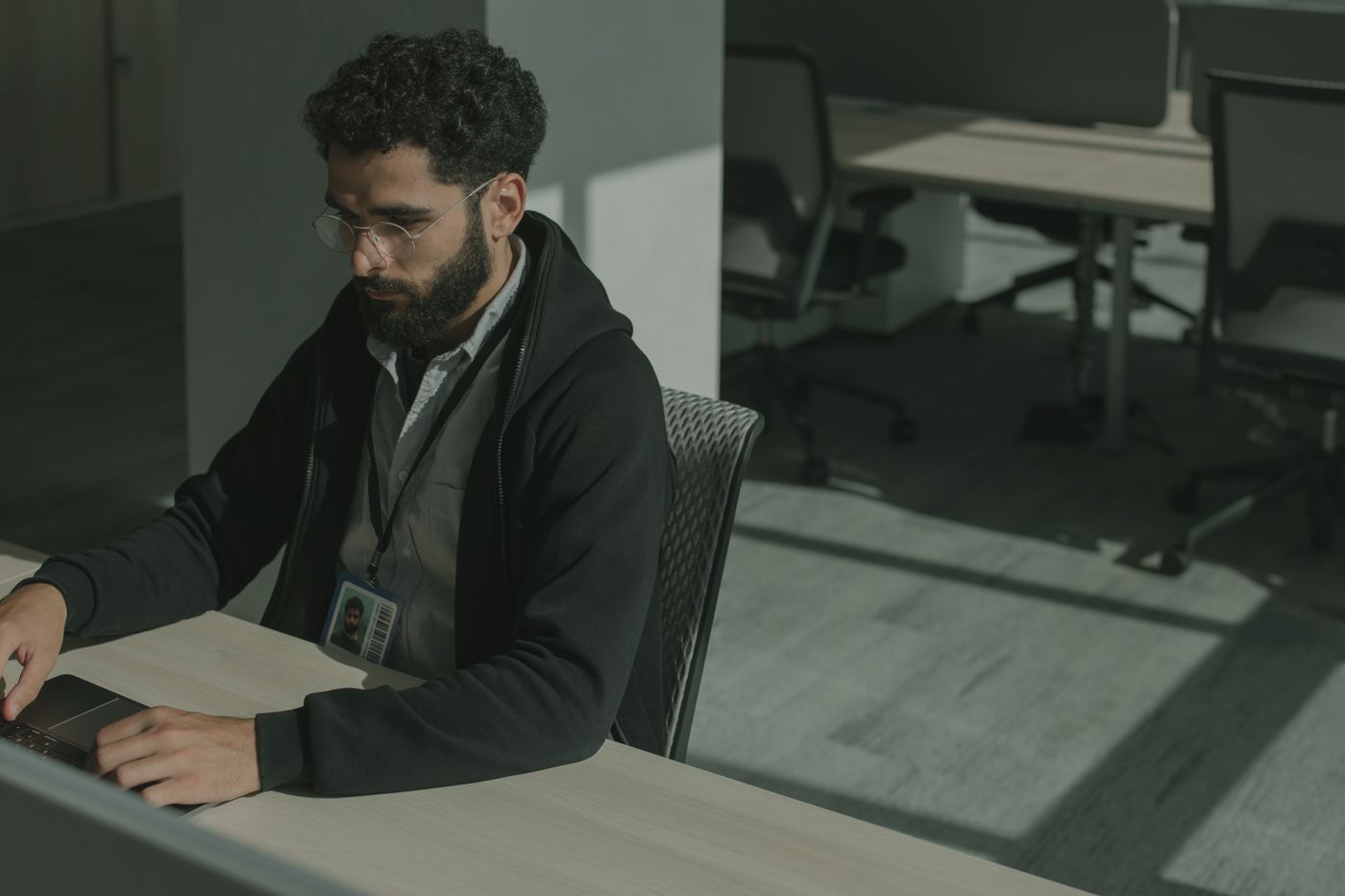 Security professional with an ID badge working at a computer in a modern office