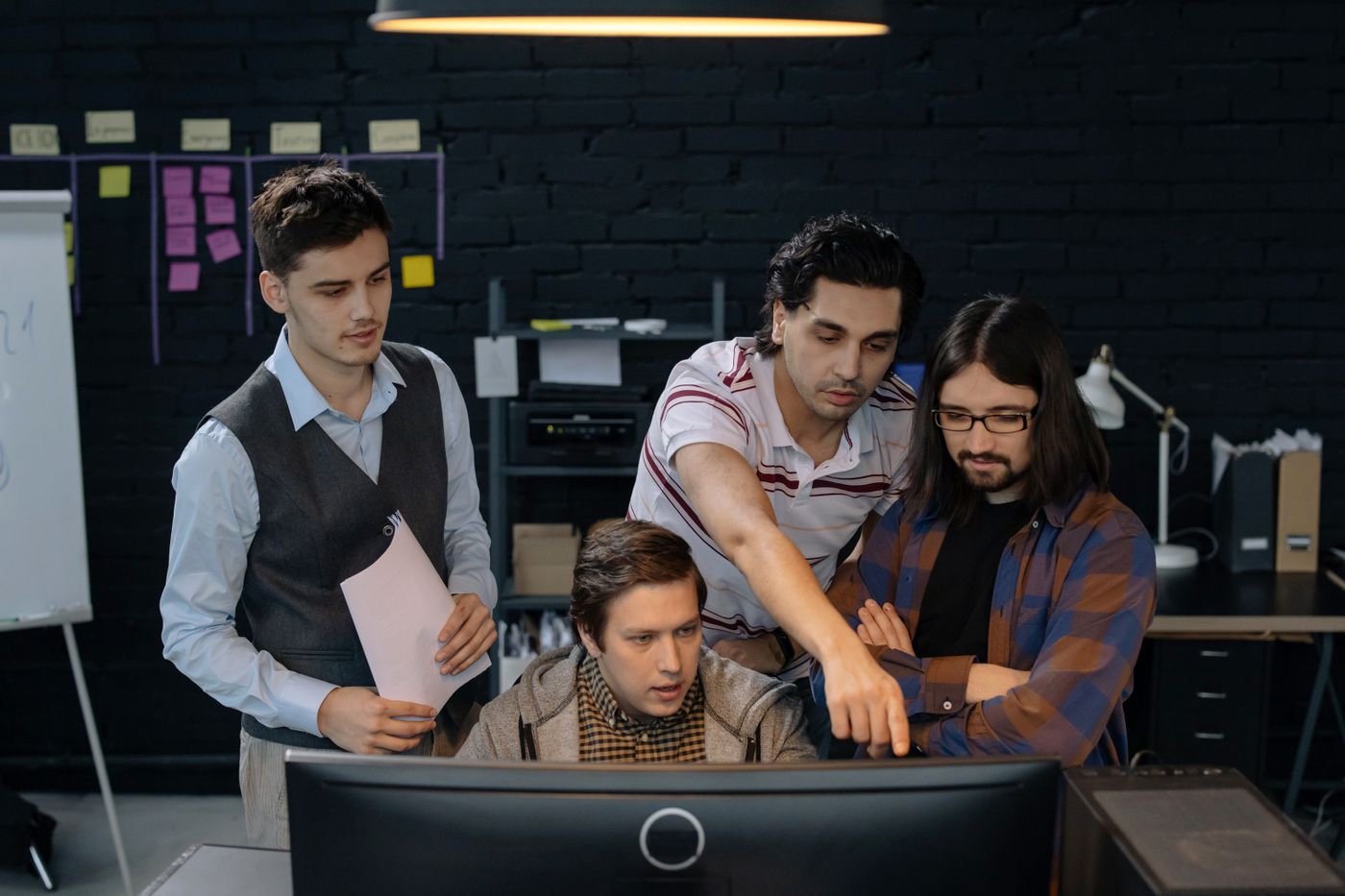 Tech team discussing a project together at a computer in a modern office