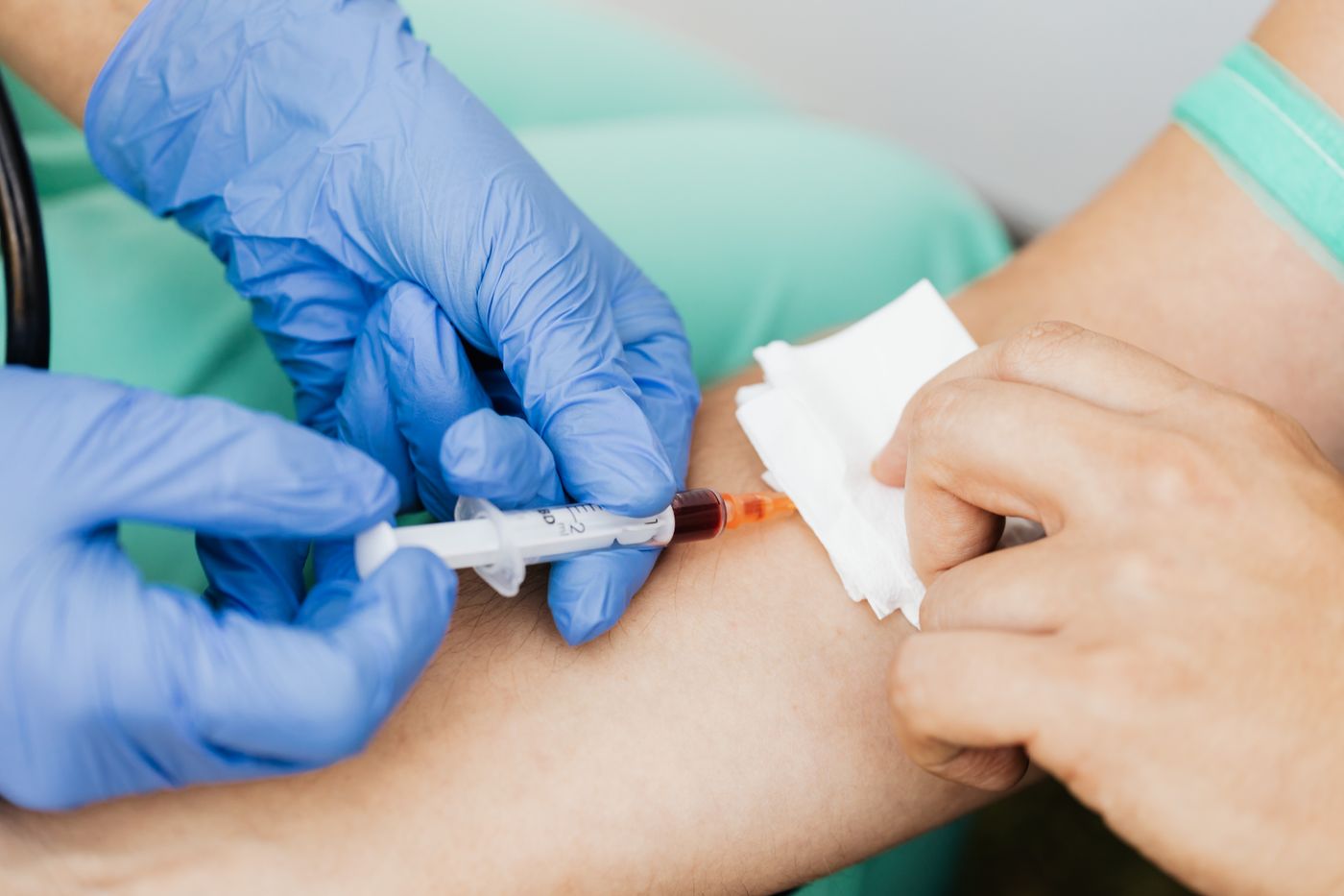 Gloved healthcare professional drawing a blood sample from a patient’s arm