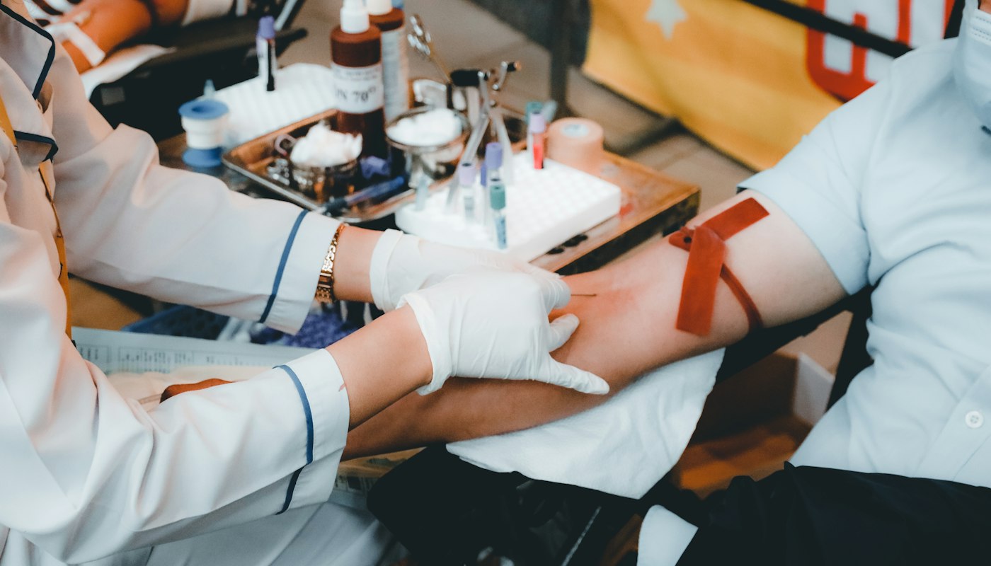 Healthcare worker in white gloves preparing a patient’s arm for a blood draw