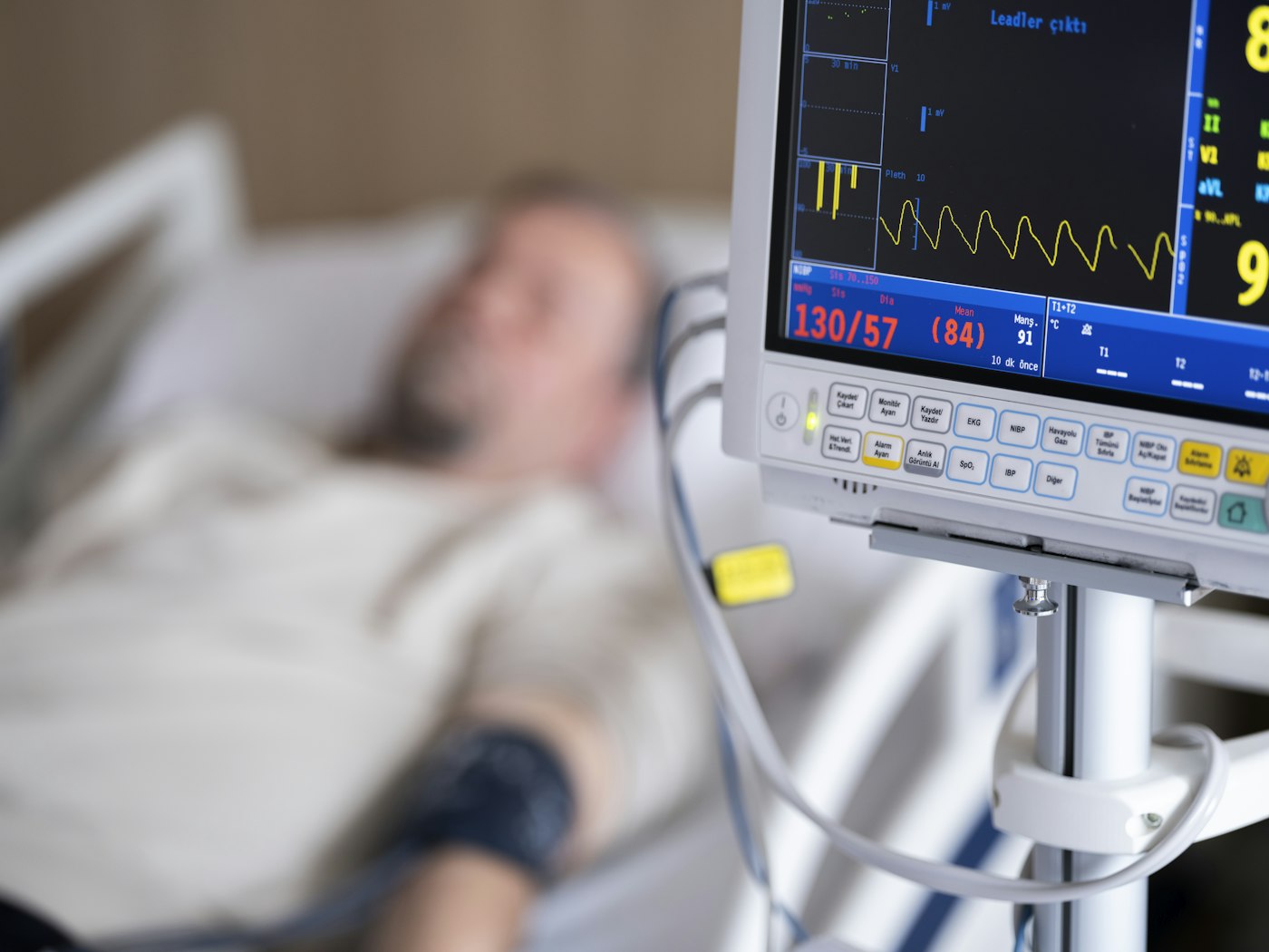 Patient resting in a hospital bed beside a heart monitor displaying ECG readings